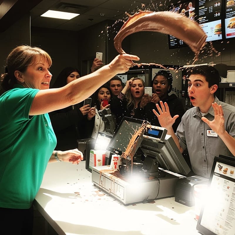 Woman hurling a milkshake at a cashier in a store.